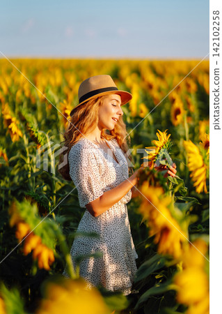 Happy woman posing in a field of sunflowers in hat. Fashion, lifestyle, travel and vacations concept Happy woman posing in a field of sunflowers in hat. Fashion, lifestyle, travel and vacations concept 142102258