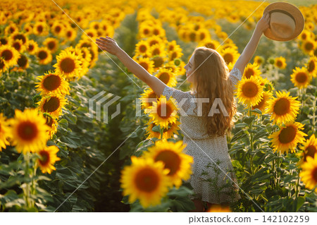 Happy woman posing in a field of sunflowers in hat. Fashion, lifestyle, travel and vacations concept 142102259