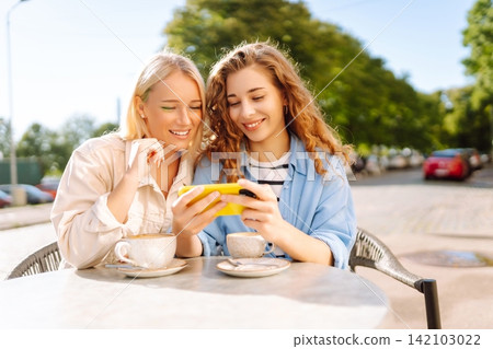Smiling woman are sitting in a cafe, taking selfies, talking with friends. Fashion, beauty. Smiling woman are sitting in a cafe, taking selfies, talking with friends. Fashion, beauty. 142103022