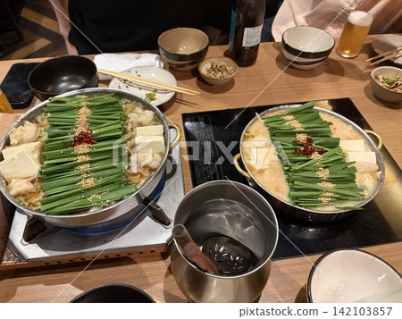 日本酒吧的一幕:人們圍坐在盛滿韭菜的火鍋旁。 日本酒吧的一幕:人們圍坐在盛滿韭菜的火鍋旁。 142103857