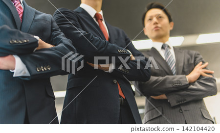 Three men with their arms crossed, viewed from a low angle. Three men with their arms crossed, viewed from a low angle. 142104420