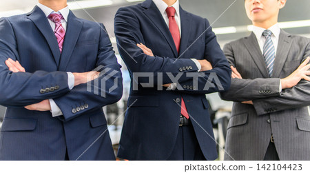 Three men in suits with their arms crossed, symbolizing business camaraderie. Three men in suits with their arms crossed, symbolizing business camaraderie. 142104423