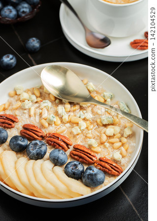 Oatmeal. Bowl of oatmeal porridge with blackberry, bananas and chia seeds on gray concrete old table background. Top view in flat lay style. Natural ingredients. Hot healthy breakfast and diet food Oatmeal. Bowl of oatmeal porridge with blackberry, bananas and chia seeds on gray concrete old table background. Top view in flat lay style. Natural ingredients. Hot healthy breakfast and diet food 142104529