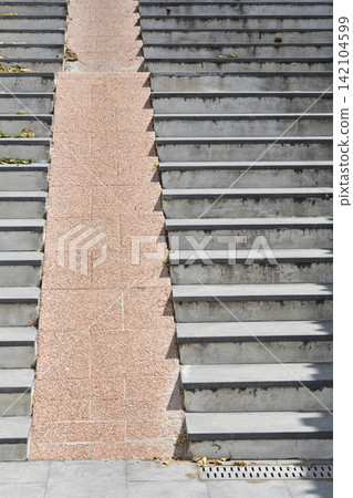 Wide outdoor concrete staircase with a stone bicycle ramp and shadows Wide outdoor concrete staircase with a stone bicycle ramp and shadows 142104599