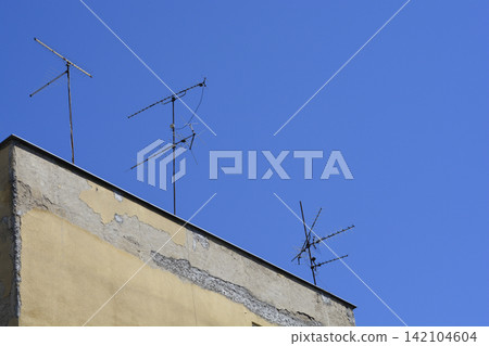 Old television antennas on a building roof against blue sky Old television antennas on a building roof against blue sky 142104604