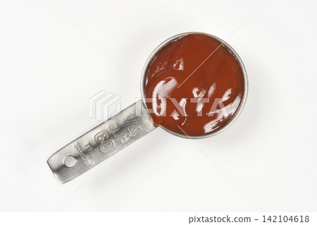Ketchup in a metal measuring cup on white background Ketchup in a metal measuring cup on white background 142104618