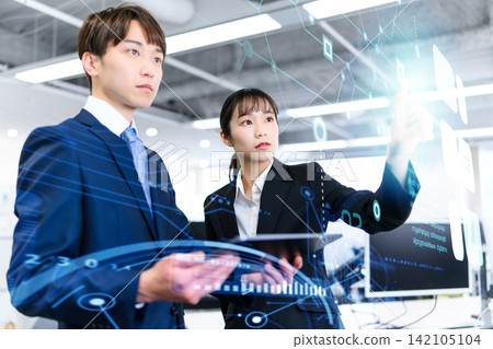 A male and female business professional giving an explanation using a tablet. A male and female business professional giving an explanation using a tablet. 142105104