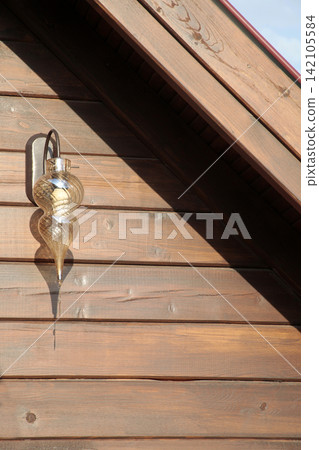 street lamp hangs high under the roof of a wooden house street lamp hangs high under the roof of a wooden house 142105584