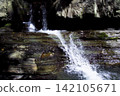 Waterfall Cascading Over Layered Rocks in Forest 142105671