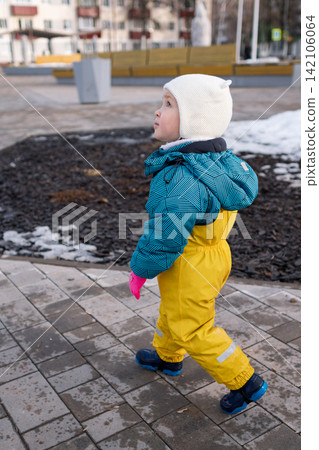 Curious toddler exploring winter playground environment outdoors Curious toddler exploring winter playground environment outdoors 142106064