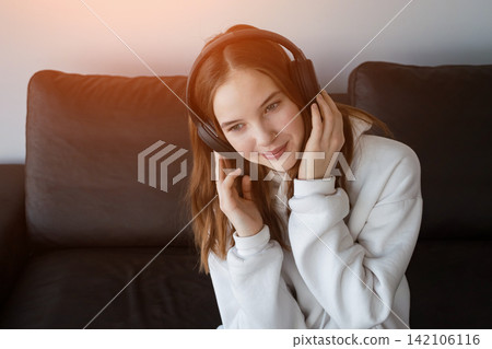 Young woman enjoying music with headphones relaxing at home 142106116