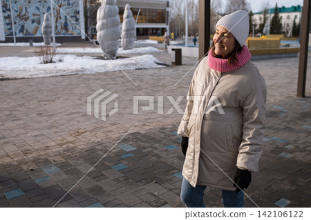 Pregnant woman walking outdoors in winter park wearing warm coat and knitted hat Pregnant woman walking outdoors in winter park wearing warm coat and knitted hat 142106122