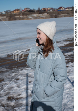 Young woman enjoying phone conversation during winter walk 142106136