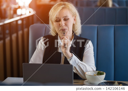 Thoughtful Senior Entrepreneur. Elderly Lady Contemplating Ideas During Meal Break. Older Female Professional Engages In Silent Brainstorming During Relaxed Midday Meal In Cozy Surroundings Thoughtful Senior Entrepreneur. Elderly Lady Contemplating Ideas During Meal Break. Older Female Professional Engages In Silent Brainstorming During Relaxed Midday Meal In Cozy Surroundings 142106146