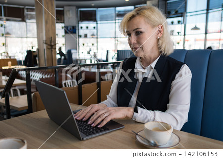 Elderly Businesswoman Working On Laptop Cafe, Focused On Email And Scheduling During Lunch Break, Cup Of Coffee On Table, Modern Bistro Interior, Natural Daylight, Relaxed Yet Professional Atmosphere Elderly Businesswoman Working On Laptop Cafe, Focused On Email And Scheduling During Lunch Break, Cup Of Coffee On Table, Modern Bistro Interior, Natural Daylight, Relaxed Yet Professional Atmosphere 142106153