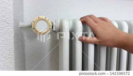 Hand checking warm radiator during home heating maintenance temperature inspection comfort control energy efficiency Hand checking warm radiator during home heating maintenance temperature inspection comfort control energy efficiency 142106572