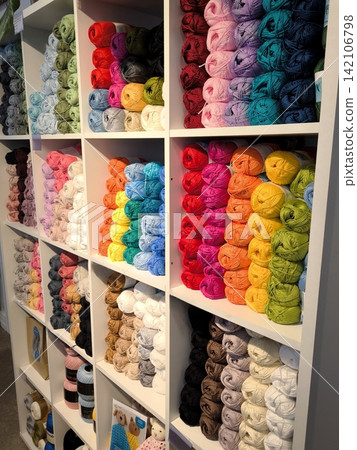 Multicolored skeins of yarn for handicrafts on the shelves in a craft store. Multicolored skeins of yarn for handicrafts on the shelves in a craft store. 142106798