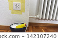 Home renovation preparation paint bucket roller and masked socket ready for wall coating interior improvement repair process detail of clean bright  142107240