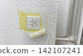 Wall socket masked with painter tape before coating surface protection for safe house renovation repair workflow electrical safety step clean 142107241