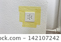Electrical socket covered with masking tape protection before painting home renovation stage preparation for interior repair safety wall edge detail  142107242