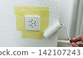 Painting wall around masked power socket with small roller home renovation and repair step interior refresh careful edge work clean modern design 142107243