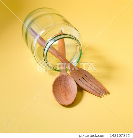 Wood spoon and fork in glass jar. 142107855