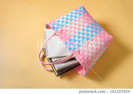 Books and notebooks in Colorful Woven Plastic Shopping Bag. Books and notebooks in Colorful Woven Plastic Shopping Bag. 142107934