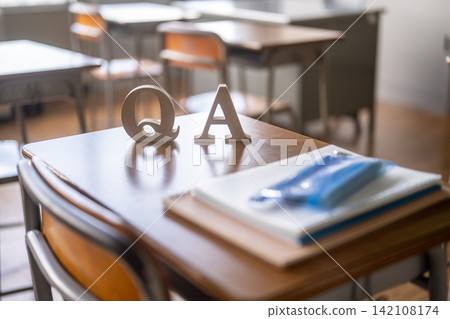 The letters "QA" and a notebook were placed on a school desk. The letters "QA" and a notebook were placed on a school desk. 142108174