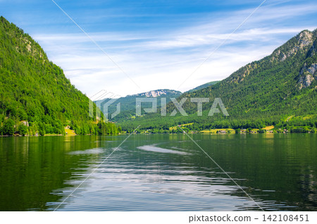 Hallstatt, Austria. A magnificent view from the lake, showcasing the beautiful natural scenery and mirror-like surface of the water in early summer. Hallstatt, Austria. A magnificent view from the lake, showcasing the beautiful natural scenery and mirror-like surface of the water in early summer. 142108451
