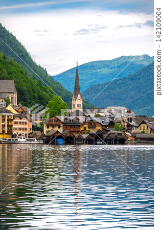Hallstatt, Austria. A beautiful lakeside village with church spires reflected in the lake and traditional townscape. 142109004