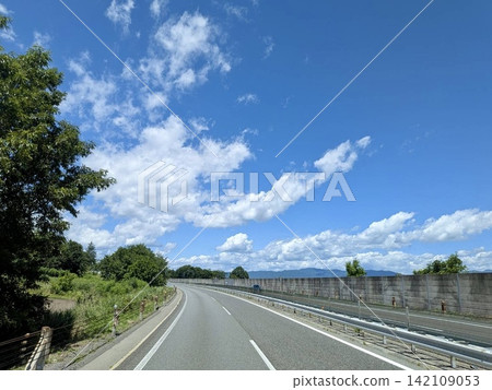 A winding highway running through the summer blue sky and greenery. A winding highway running through the summer blue sky and greenery. 142109053