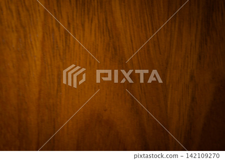 Warm brown wooden surface showing intricate grain patterns, creating a rustic background texture for design and decorative projects Warm brown wooden surface showing intricate grain patterns, creating a rustic background texture for design and decorative projects 142109270