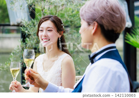 一張新郎新娘在水邊露台上喝香檳的婚禮照片。 一張新郎新娘在水邊露台上喝香檳的婚禮照片。 142110003