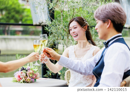A wedding image of a bride and groom drinking champagne with friends. A wedding image of a bride and groom drinking champagne with friends. 142110015