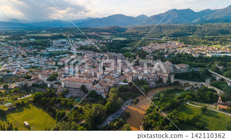 Aerial panoramic view of Besalu medieval town and historic stone bridge in Catalonia Spain surrounded by mountains and green countryside at sunset Aerial panoramic view of Besalu medieval town and historic stone bridge in Catalonia Spain surrounded by mountains and green countryside at sunset 142110362