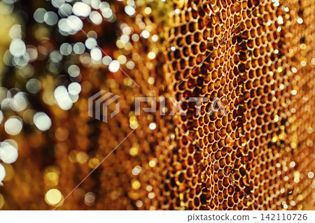 Macro close up of fresh raw liquid honey filled inside wax honeycomb cells texture background Macro close up of fresh raw liquid honey filled inside wax honeycomb cells texture background 142110726