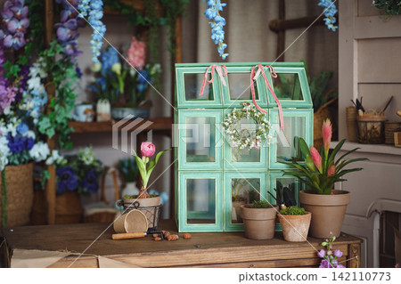 Vintage green mini greenhouse terrarium on wooden table with potted plants Vintage green mini greenhouse terrarium on wooden table with potted plants 142110773