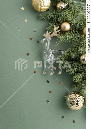 Christmas festive sparkling reindeer ornament and pine branches with baubles scattered stars against plain background Christmas festive sparkling reindeer ornament and pine branches with baubles scattered stars against plain background 142110927