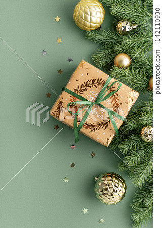 Festive Christmas Gift Box Surrounded by Pine Branches and Baubles with Star Confetti Scattered Festive Christmas Gift Box Surrounded by Pine Branches and Baubles with Star Confetti Scattered 142110930