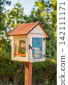Small outdoor community book exchange box filled with books in green city park. Free library encourages reading, book sharing, literacy, reuse and access to books in public spaces 142111171