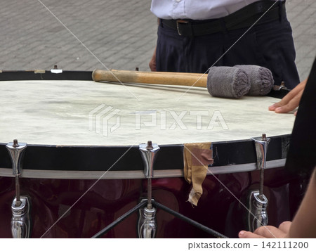 Large ceremonial bass drum with mallets rests on top as band member prepares to perform during parade festivities Large ceremonial bass drum with mallets rests on top as band member prepares to perform during parade festivities 142111200