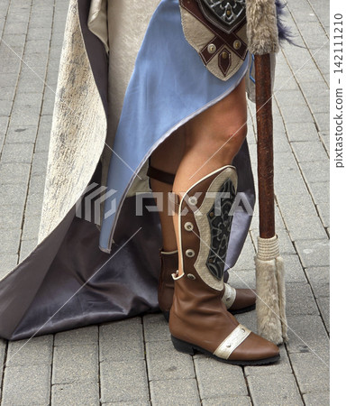 Side view of historical costume featuring boots and cape on paved street Side view of historical costume featuring boots and cape on paved street 142111210