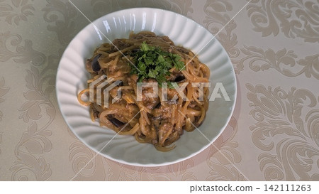 Spaghetti pasta with meat sauce and green herbs on a plate 142111263