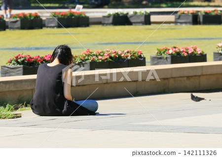 The back view of a woman sitting on the ground The back view of a woman sitting on the ground 142111326