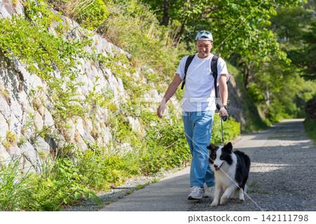 一名男子正在遛他的邊境牧羊犬。 一名男子正在遛他的邊境牧羊犬。 142111798