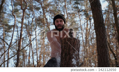 Muscular bearded guy chopping firewood in sunny winter forest. Shirtless young man working with axe in snowy woodland. Concept of strength, masculine, energy and harmony with nature during cold season Muscular bearded guy chopping firewood in sunny winter forest. Shirtless young man working with axe in snowy woodland. Concept of strength, masculine, energy and harmony with nature during cold season 142112050