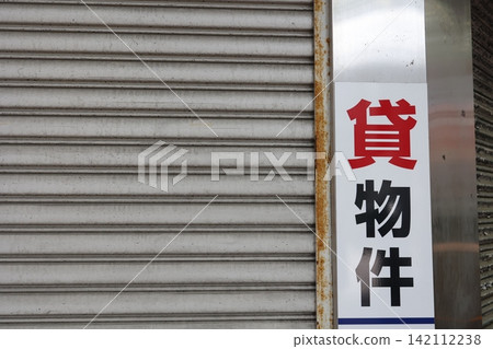 一塊出租房產廣告看板。一棟有百葉窗的建築物。房地產租賃公司的圖片。 一塊出租房產廣告看板。一棟有百葉窗的建築物。房地產租賃公司的圖片。 142112238