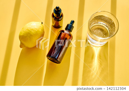 Citrus essential oil bottles with fresh lemon and water Citrus essential oil bottles with fresh lemon and water 142112304