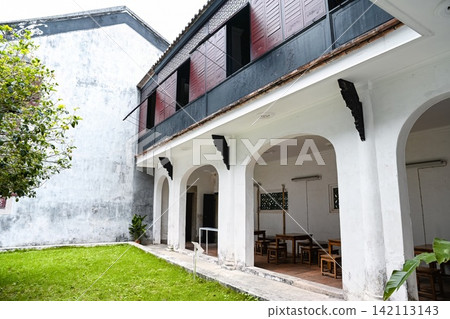 Traditional courtyard of Mandarin House built in 1869 with white arched arcade porch wooden shutters and green lawn 142113143
