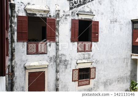 Traditional facade of Mandarin House built in 1869 featuring weathered concrete walls wooden shutters and lattices Traditional facade of Mandarin House built in 1869 featuring weathered concrete walls wooden shutters and lattices 142113146